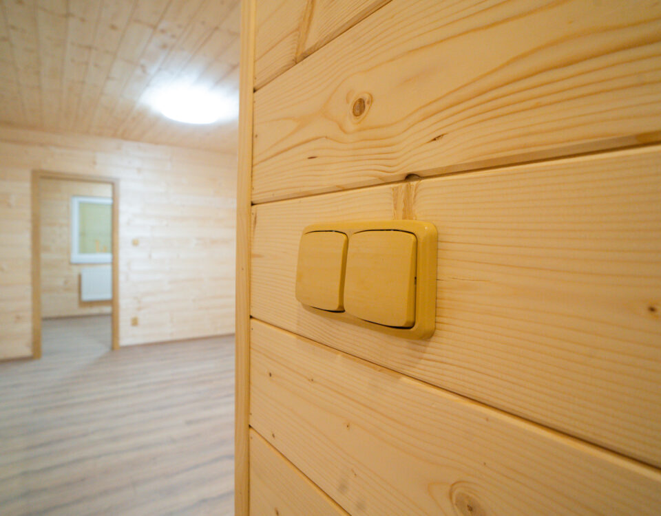 Dřevěná stěna s vypínačem v mobilním domku ABODES.