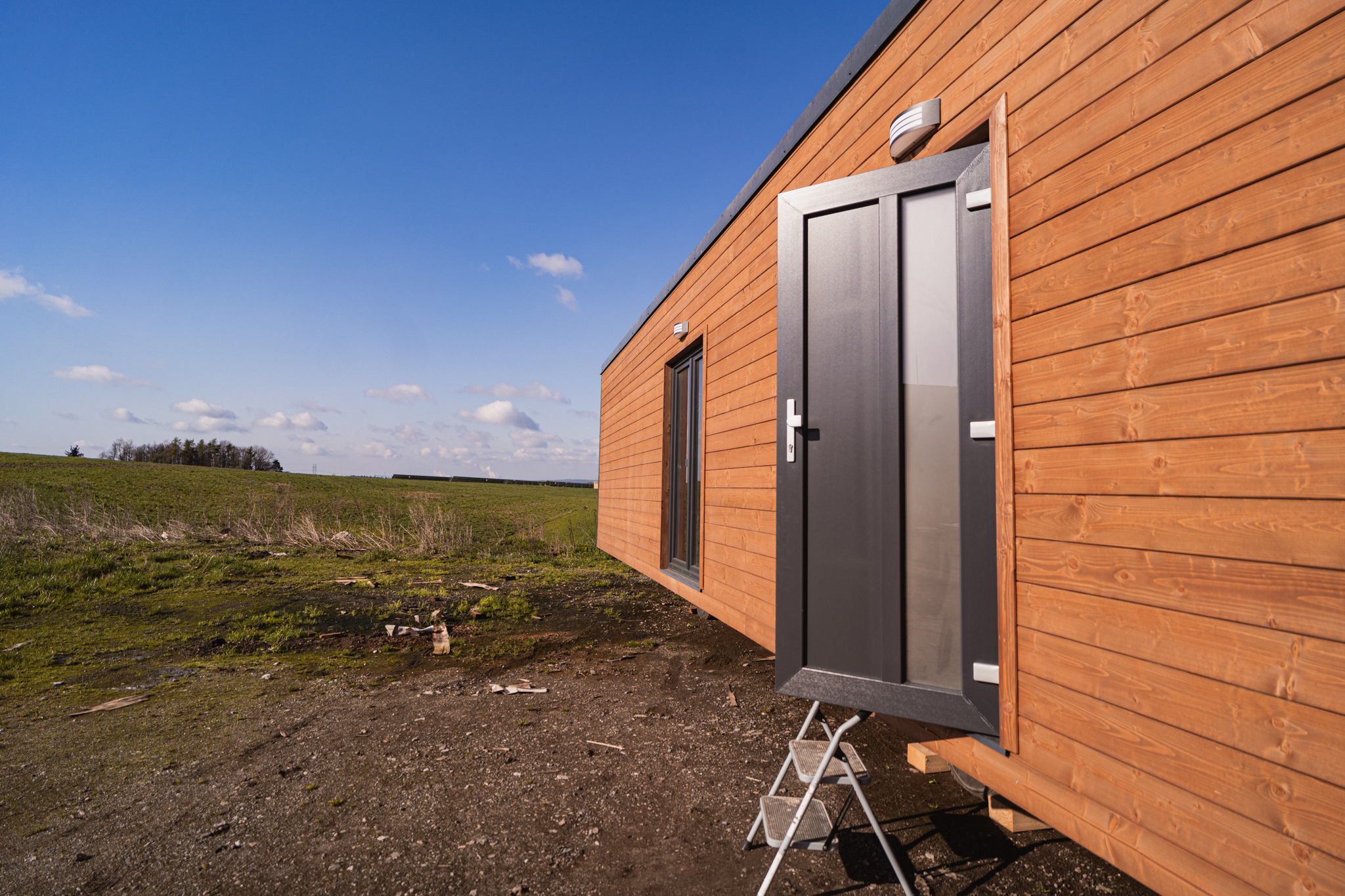 Boční pohled na dřevěný mobilní dům ABODES na pozemku.